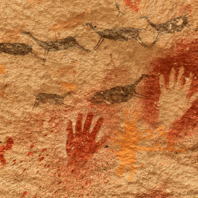 A cave painting showing running animals and red handprints