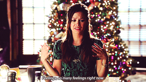 A dark-haired white woman (Rachel Bilson) stands in front of a Christmas tree and says "Feelings, so many feelings right now."